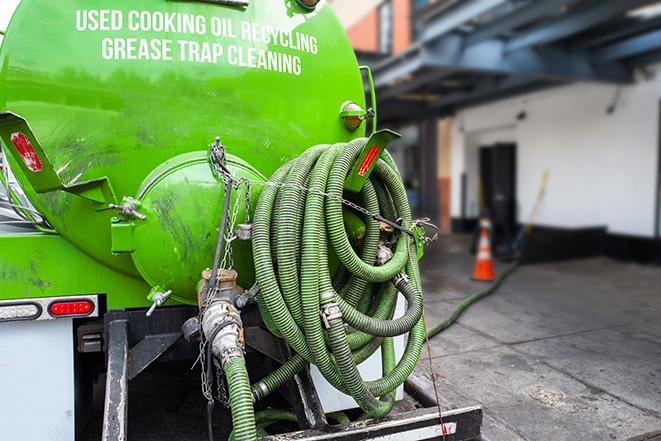 a technician pumping a grease trap in a commercial building in Acton